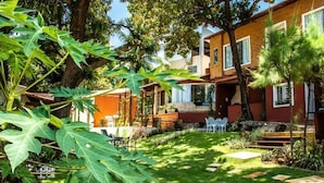 A residential area with a well-maintained garden, a patio with chairs, and a brick building with windows. - Pousada Saruê Natal (Natal)