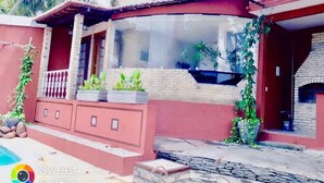 A house with a curved glass window, a brick facade, and a small pool. - Pousada Saruê Natal (Natal)