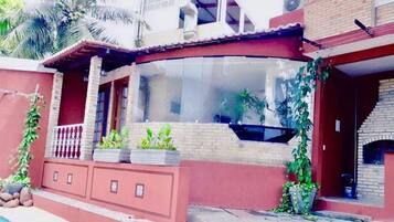 Uma casa com janela de vidro curva, fachada de tijolos e uma piscina pequena.