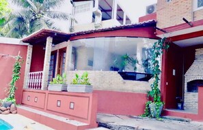 A house with a curved glass window, a brick facade, and a small pool. - Pousada Saruê Natal (Natal)