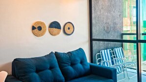 Un salón moderno con un sofá azul oscuro, un ventilador de techo y tres piezas decorativas de fibra.