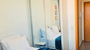 Una habitación de hotel con una cama grande, un espejo y una puerta que da a otra habitación.