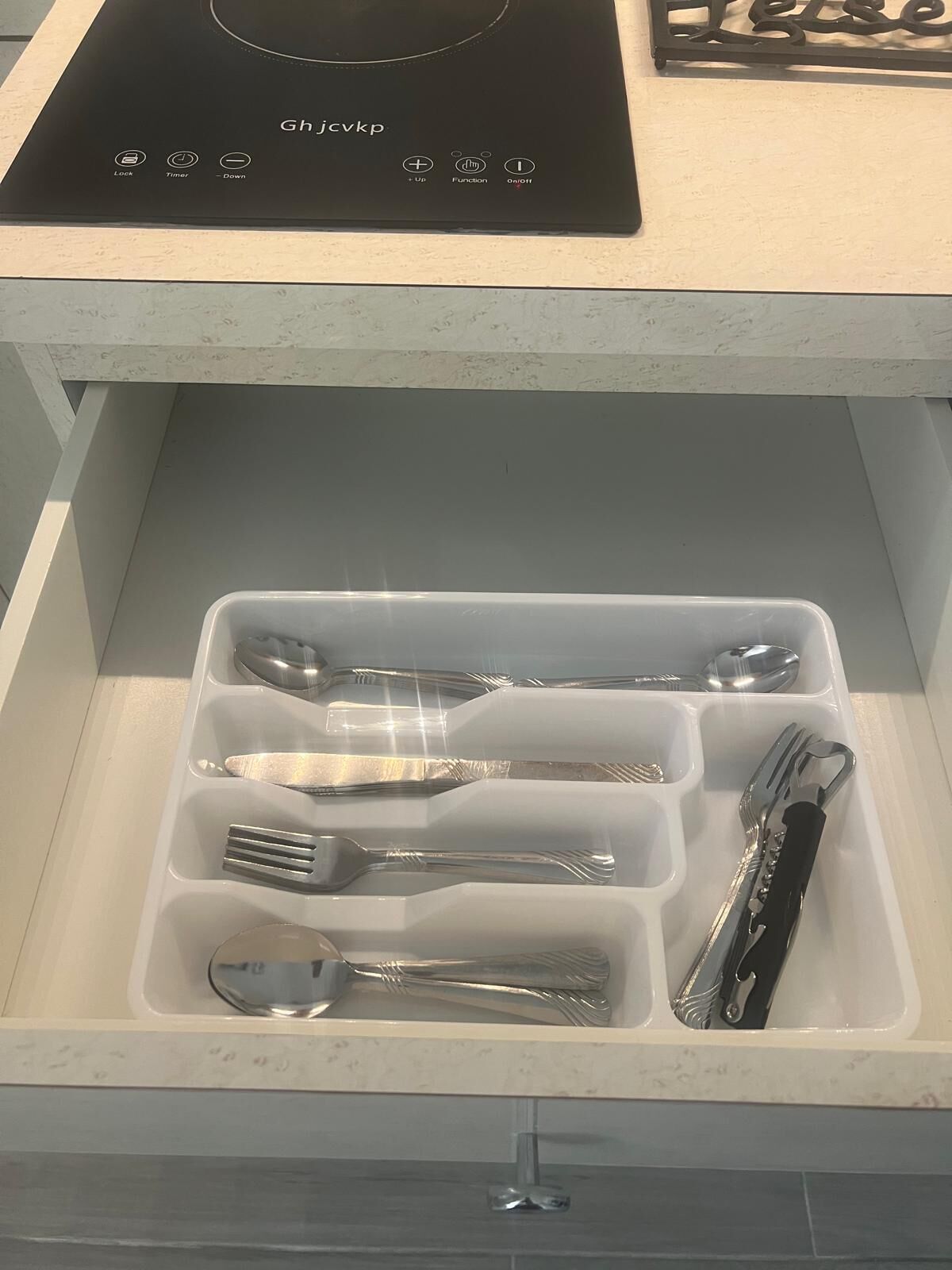 A drawer with compartments containing various kitchen utensils.