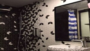 A bathroom with a geometric patterned wall, a sink with a patterned basin, and a shower area. - Zixin Hotel (Kowloon)