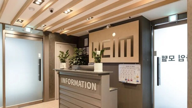 Un comptoir d’accueil avec une pancarte indiquant « RENSEIGNEMENTS » et un calendrier fixé au mur.