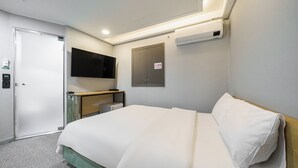 Une chambre d’hôtel équipée d’un lit, d’un téléviseur fixé au mur, d’une armoire et d’un appareil de climatisation.