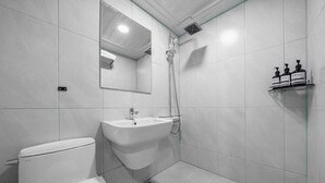 Une salle de bain moderne équipée de toilettes, d’un lavabo, d’une douche et d’un miroir.