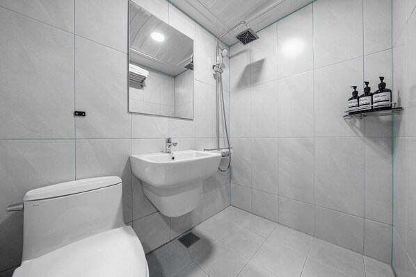 A modern bathroom with a toilet, sink, shower, and a mirror.