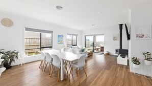 A spacious living area with a dining table, chairs, a sofa, and a fireplace. - Thyme Out with pool in Cowes (Cowes)