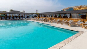 A swimming pool with lounge chairs and a covered area with a roof. - New Condo, Sleeps 6, 3 Bedroom, Beach Access, Community Pool & Private Cabanas. (Corolla)