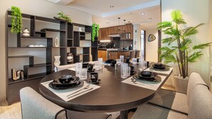 A modern dining area with a round table set for four, surrounded by dark shelving units with decorative plants. - Nowness (Mexico City)