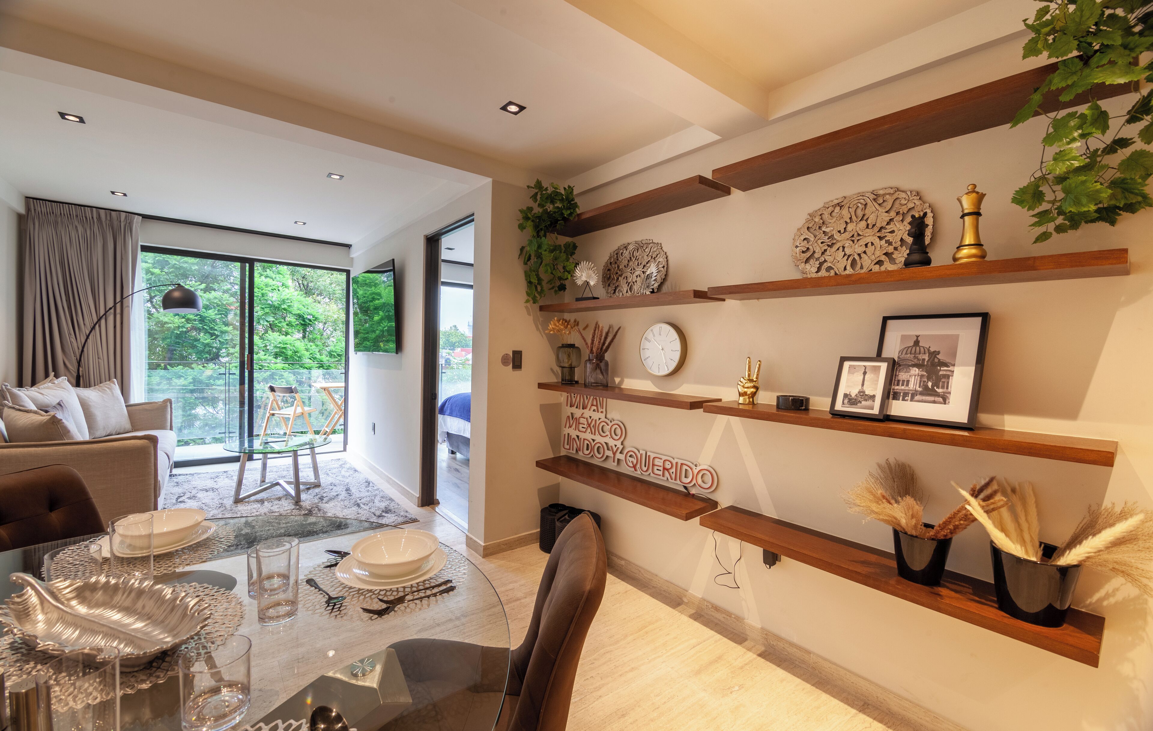 A modern dining area with a glass table, chairs, and a view of the outdoors.