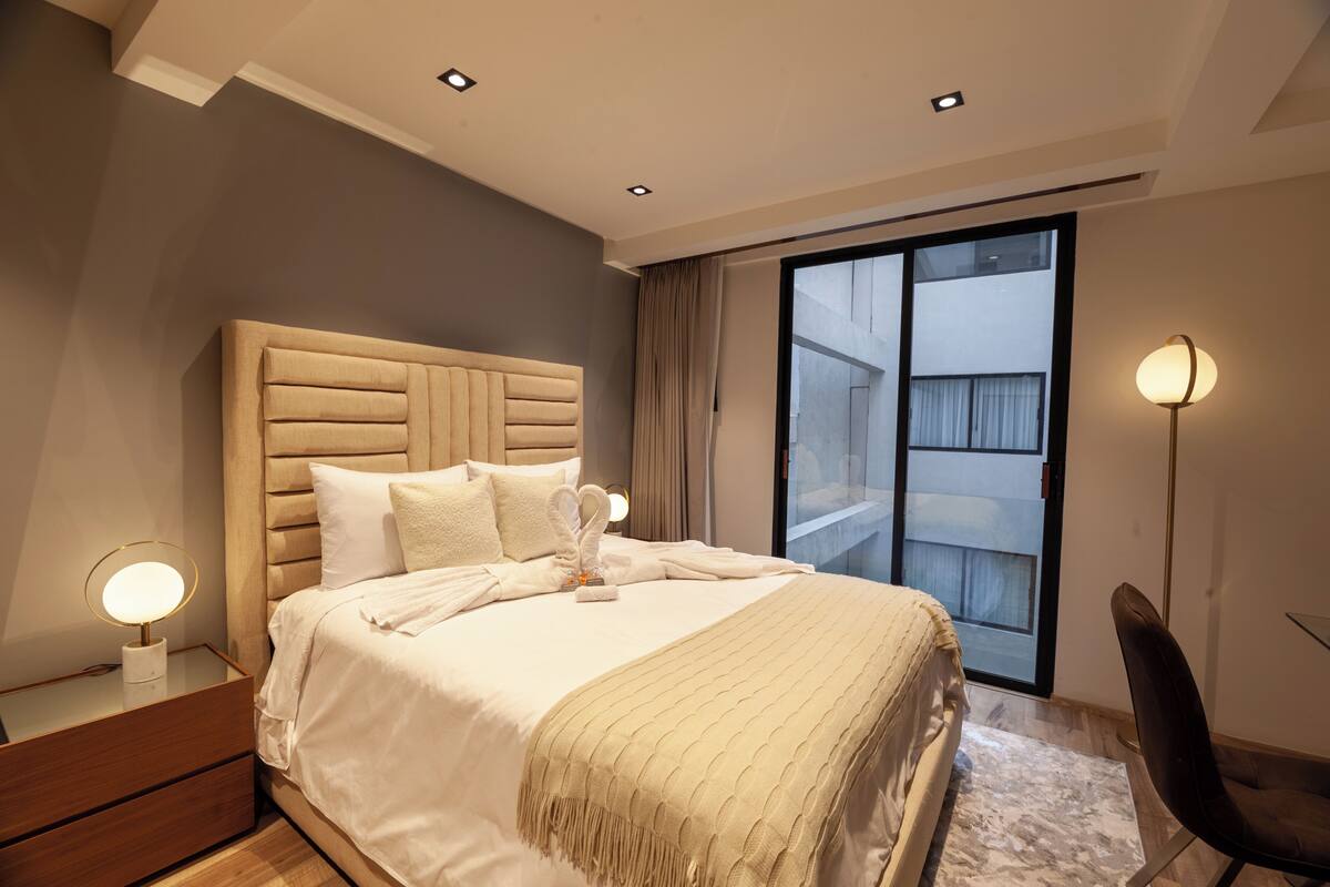 Una habitación de hotel moderna con una cama grande, un escritorio y una silla.