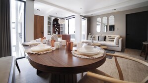 A modern living room with a round dining table set for a meal, a sofa, and a large window with curtains. - Nowness (Mexico City)