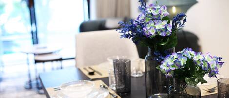 Una mesa de comedor dispuesta con platos, cubiertos y un jarrón con flores.