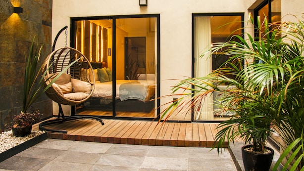 A modern hotel room with a large sliding glass door, a wicker chair, and a potted plant. - Nowness (Mexico City)
