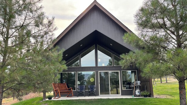 A modern house with a large glass facade, a sloped roof, and a well-maintained lawn.