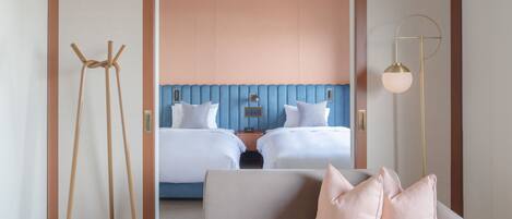 A hotel room with a bed, a sofa, a lamp, and a coat rack.