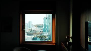 A room with a large window overlooking a cityscape, a small round table, and a chair.