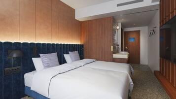 A modern hotel room with a large bed, a built-in desk, a vanity with a mirror, and a television.