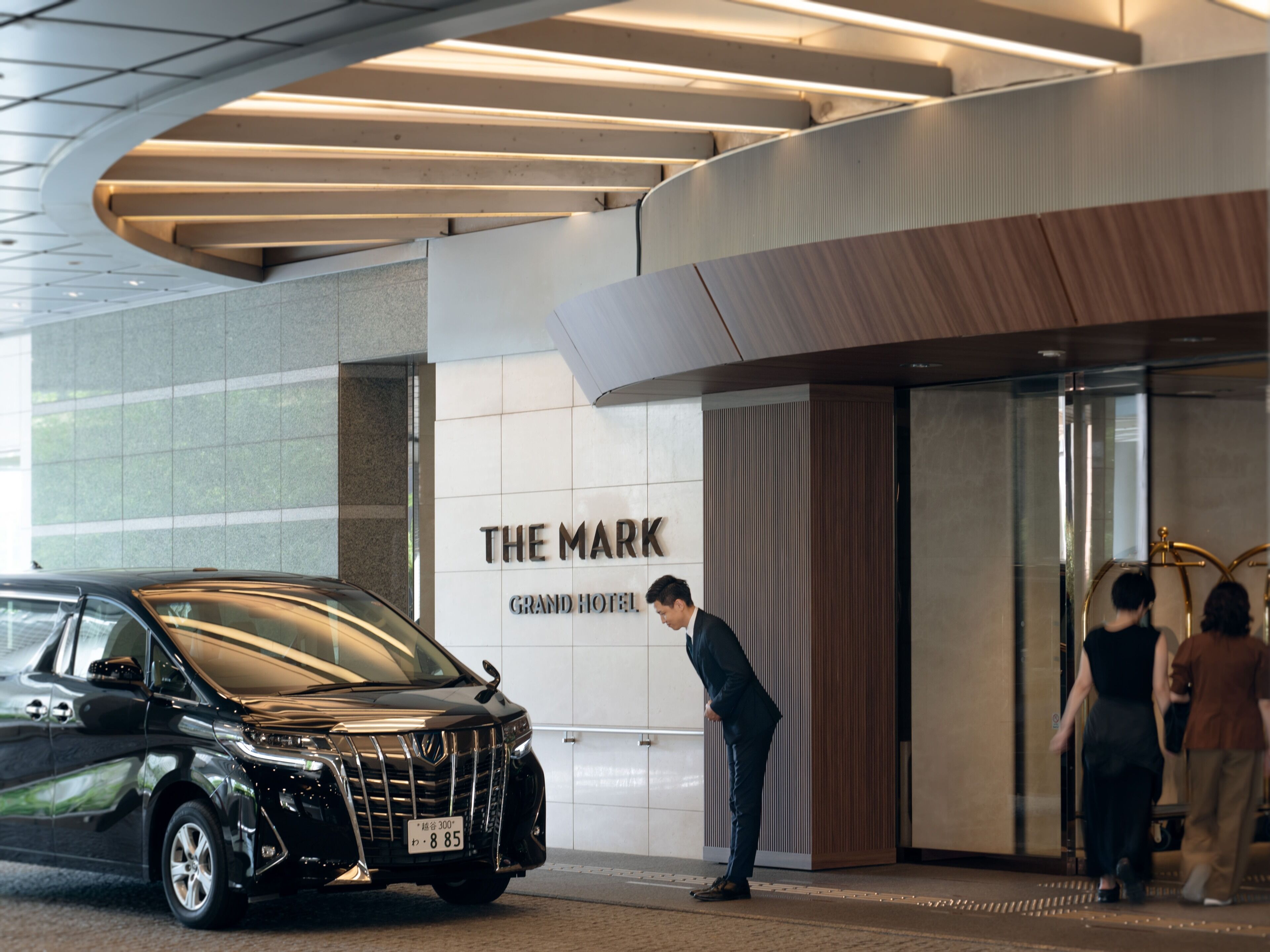 A black luxury SUV parked in front of a hotel entrance with a sign reading "THE MARK GRAND HOTEL".
