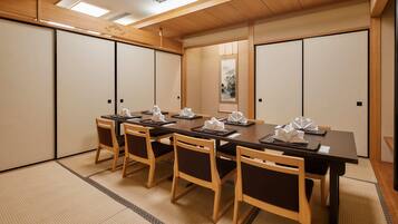 Una sala de reuniones tradicional japonesa con suelo de tatami, mesas y sillas de madera.