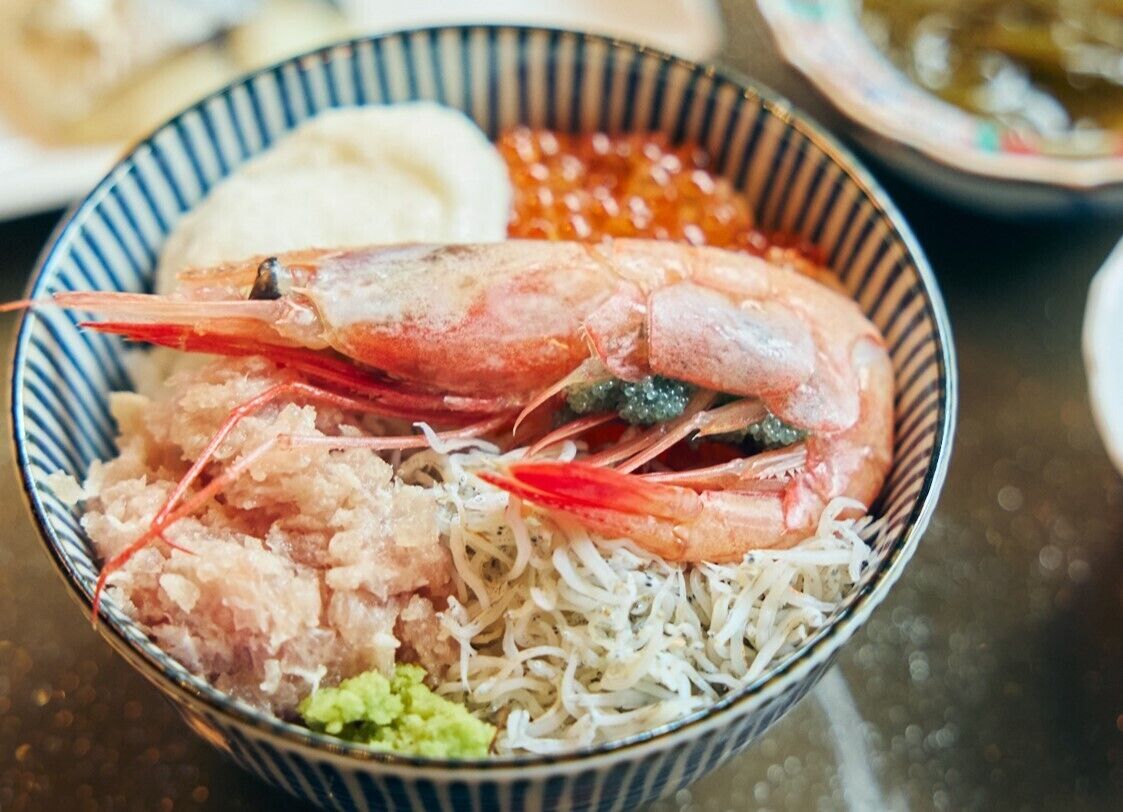 A bowl of food with shrimp, rice, and other ingredients.