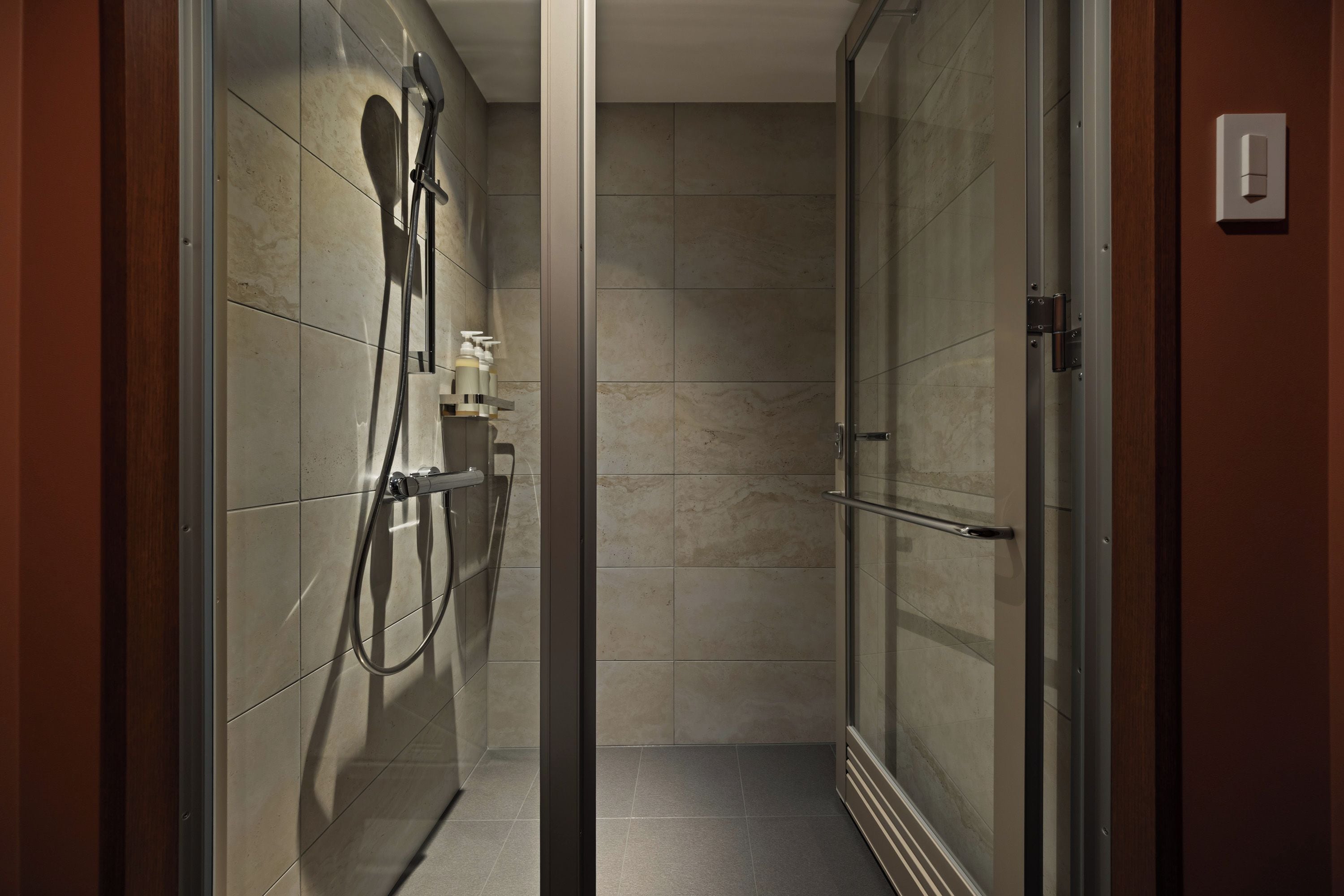 Un bagno moderno con cabina doccia in vetro, portasciuga asciugamani e dispenser di sapone.