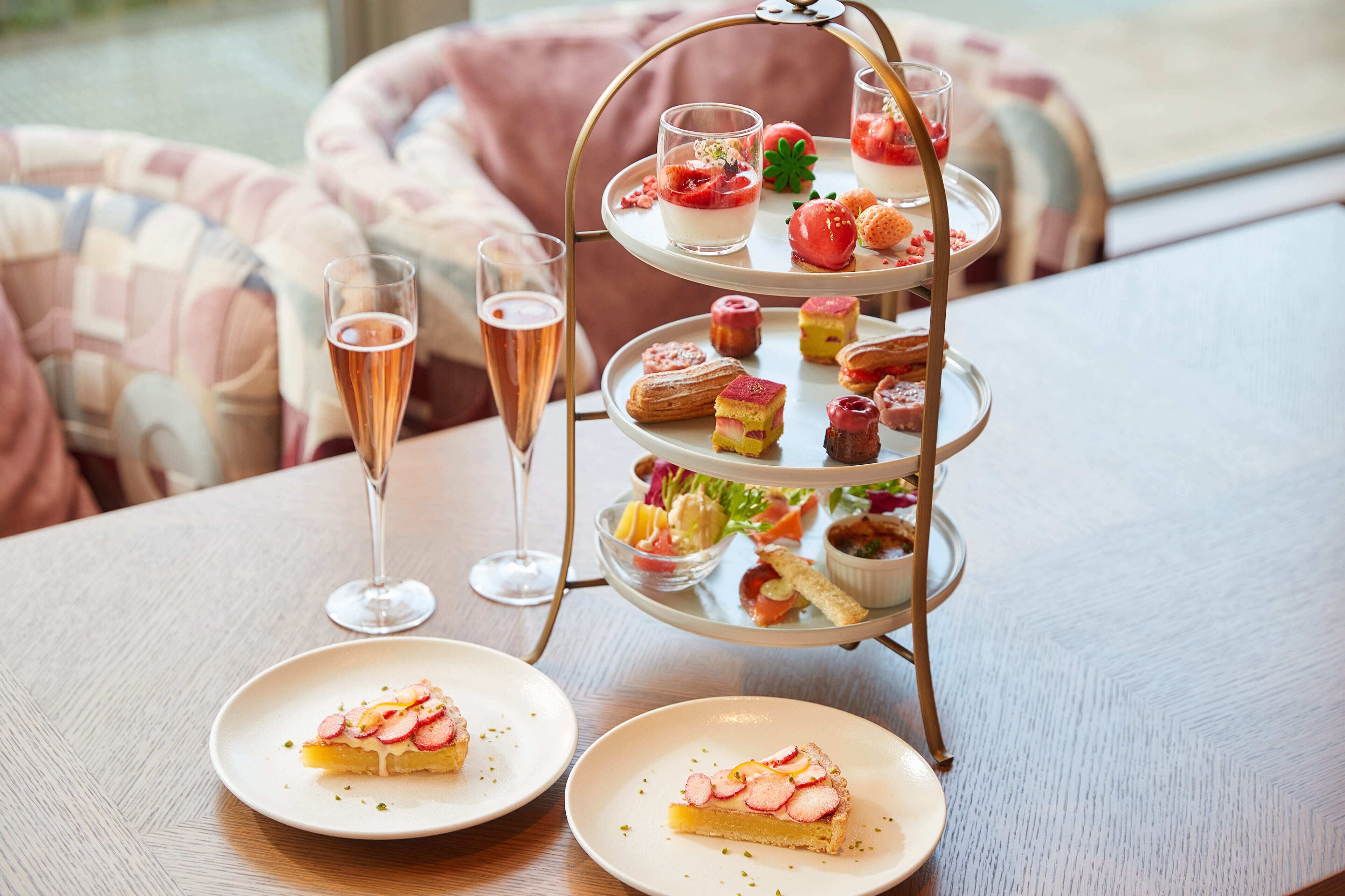 Un présentoir à étages garni de diverses pâtisseries et une coupe de champagne sur une table.