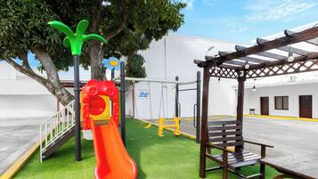 Ein Spielplatz mit Rutsche, Schaukeln und einer Bank.