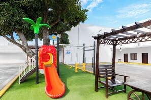 A playground with a slide, swings, and a bench.