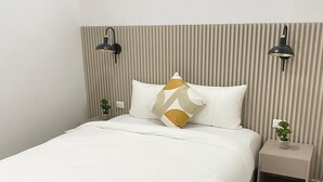 A modern bedroom with a bed, a nightstand, two wall-mounted lamps, and a potted plant. - Hotel H4  (El Paraíso)