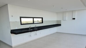 Une cuisine spacieuse et moderne, dotée d’un plan de travail noir et de meubles blancs.