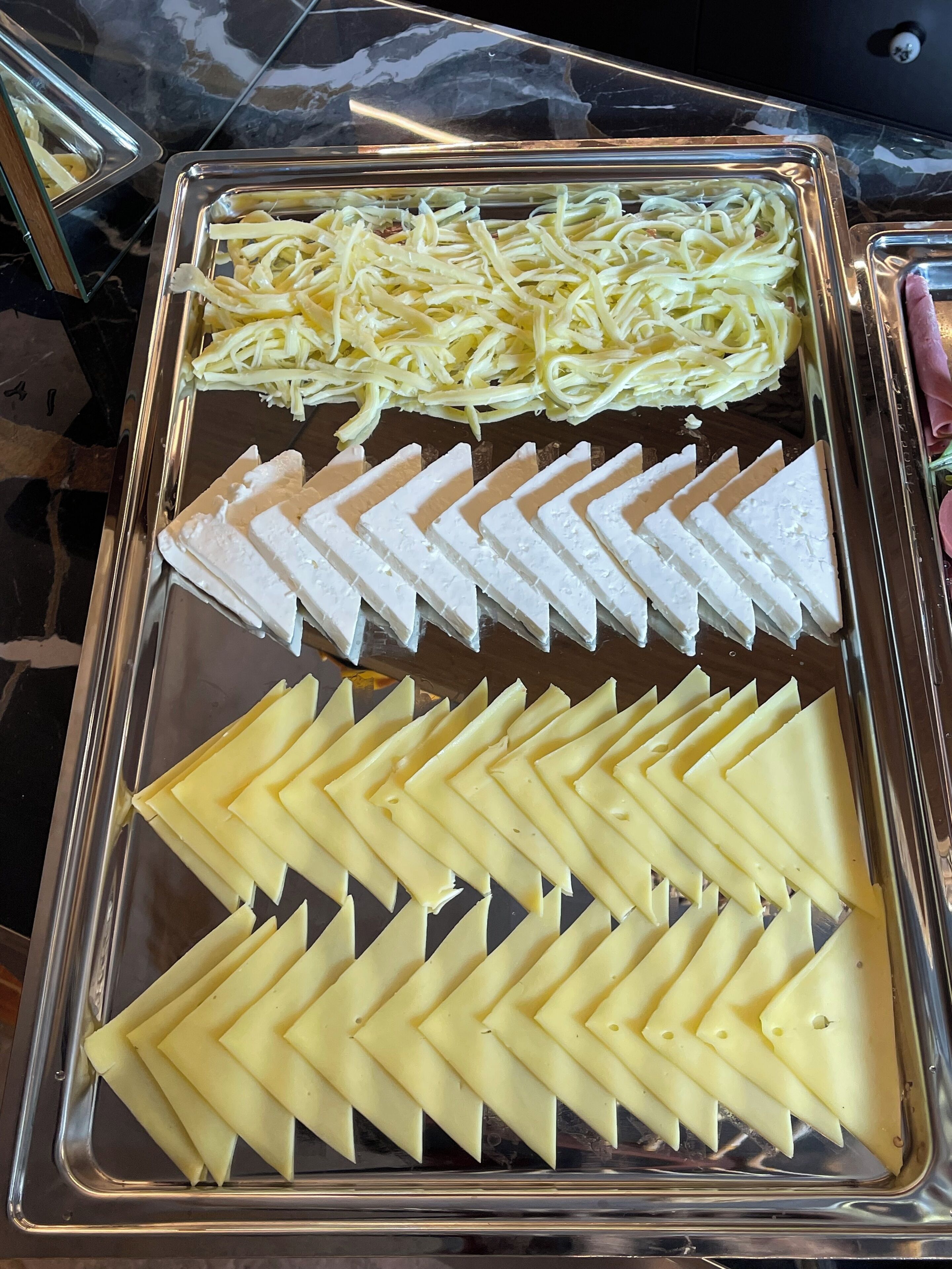 A tray with neatly arranged cheese slices and shredded cheese.