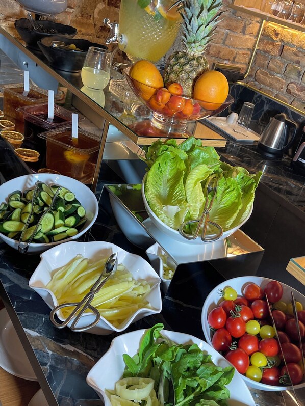 Un bufé con diversas opciones de comida, incluyendo frutas, verduras y ensaladas.