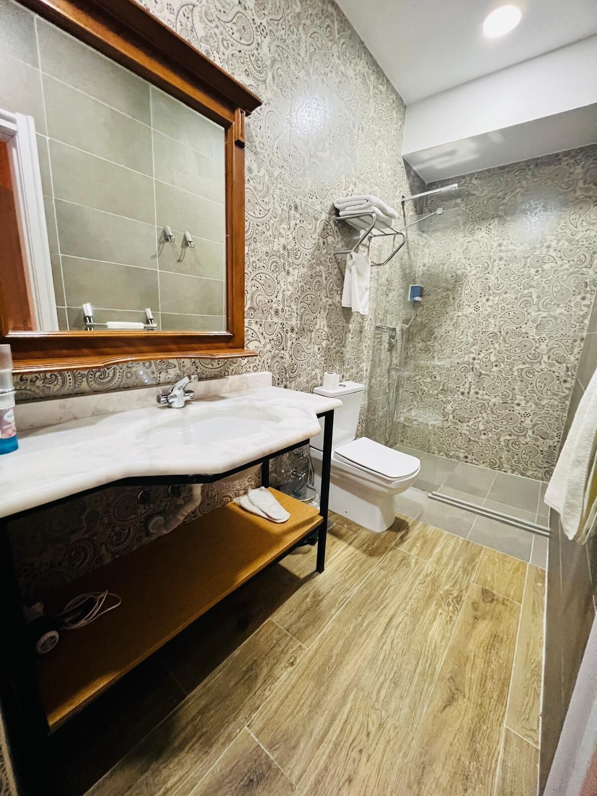 A bathroom with a marble sink, a toilet, and a glass shower enclosure.