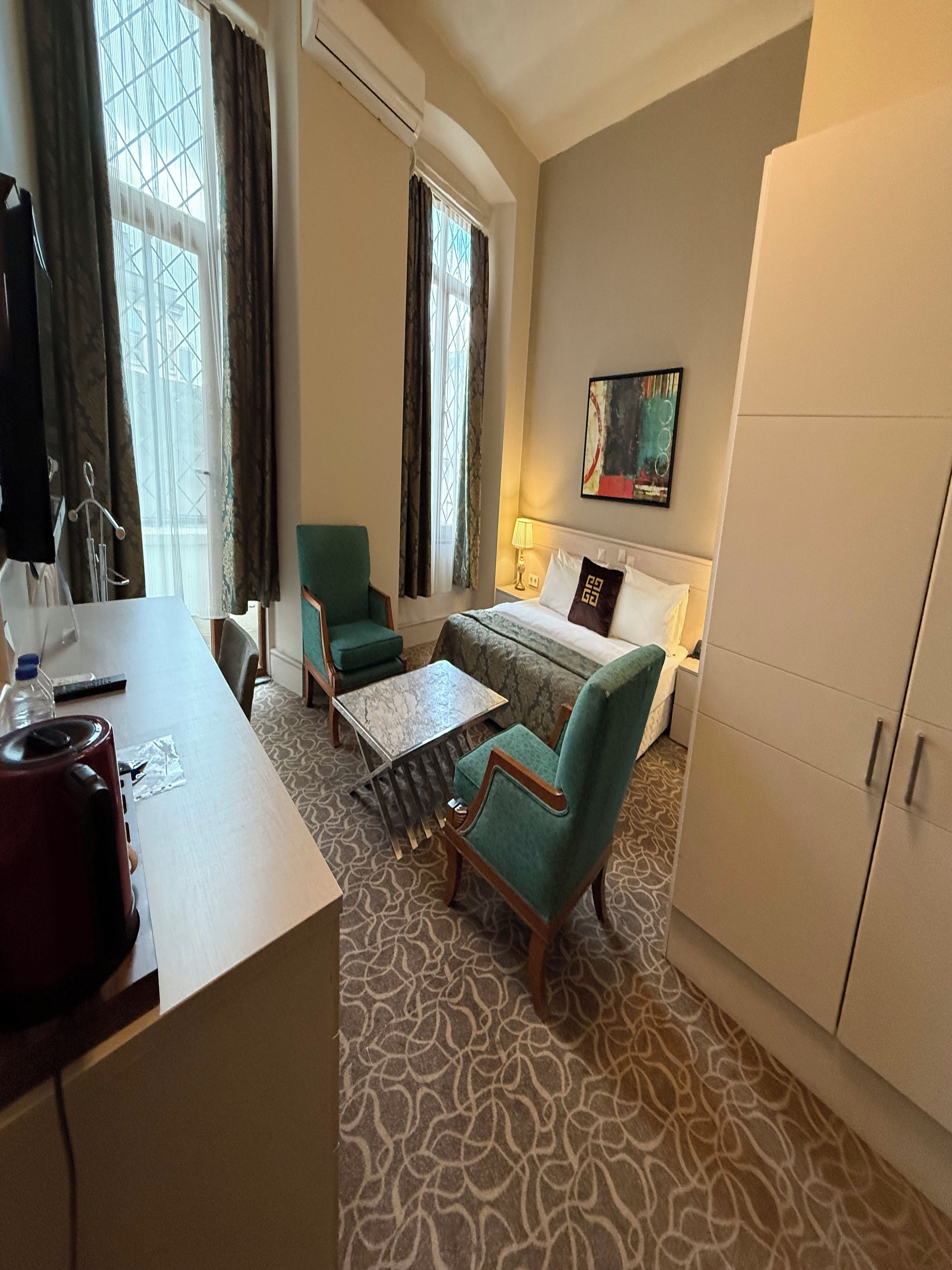 A hotel room with a bed, a desk, a chair, a sofa, and a wardrobe.