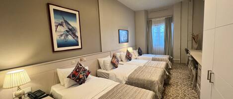 A hotel room with two beds, a desk, a chair, a TV, and a window with curtains.