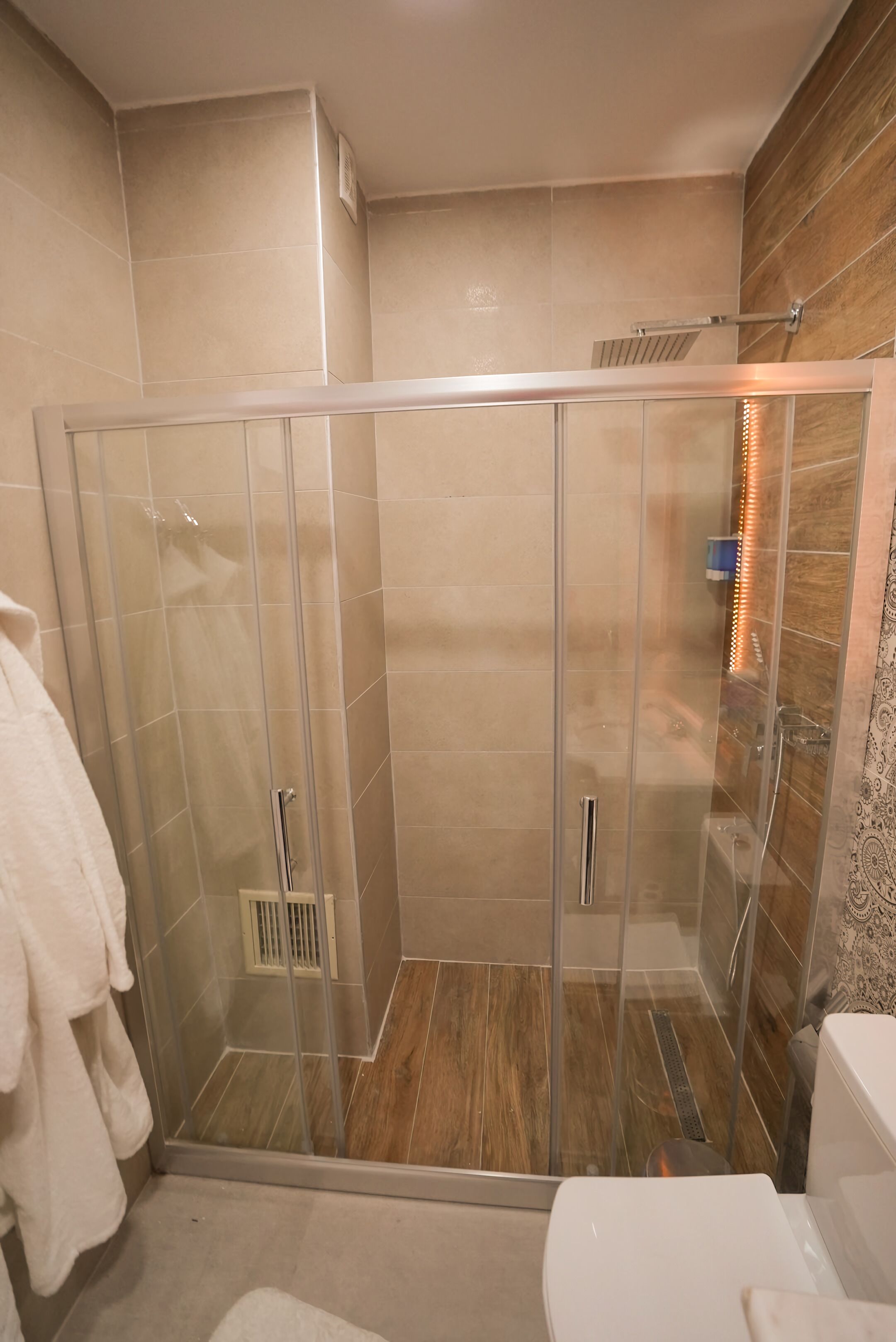 A modern bathroom with a glass-enclosed shower, a toilet, and a towel rack.