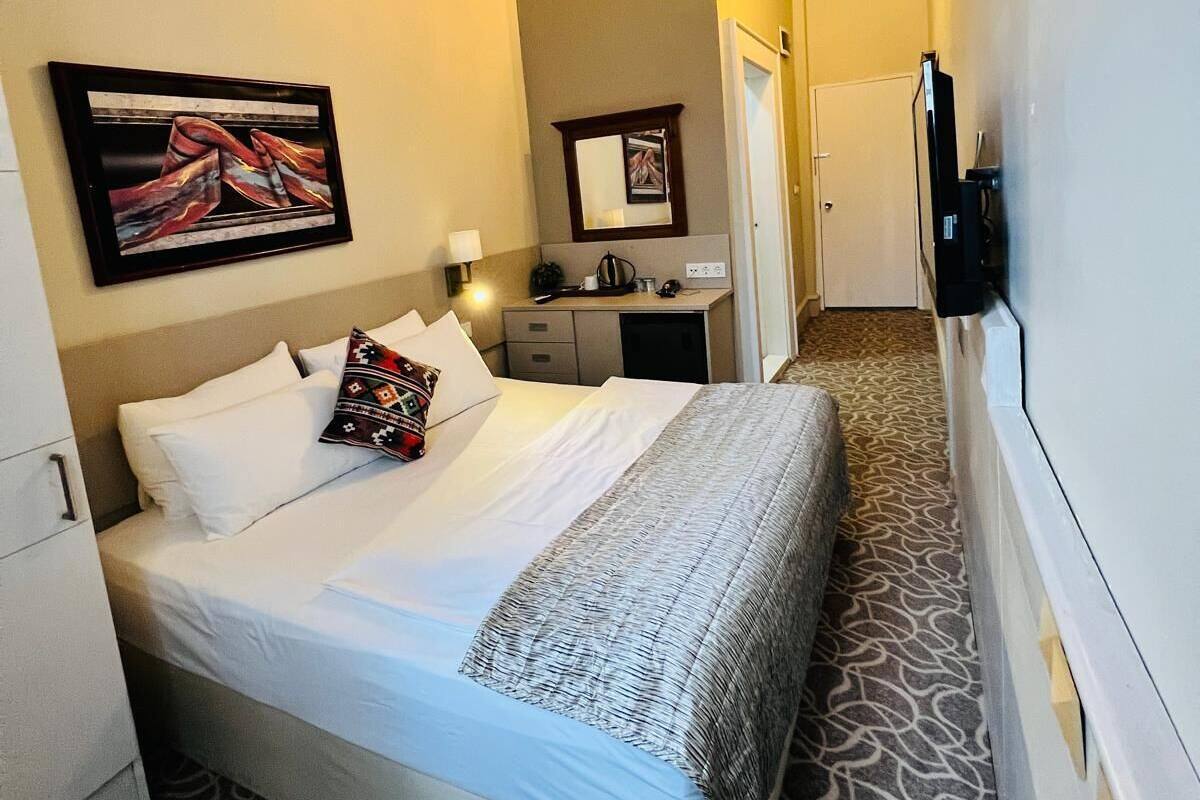 A hotel room with a bed, a desk, a mirror, and a TV.