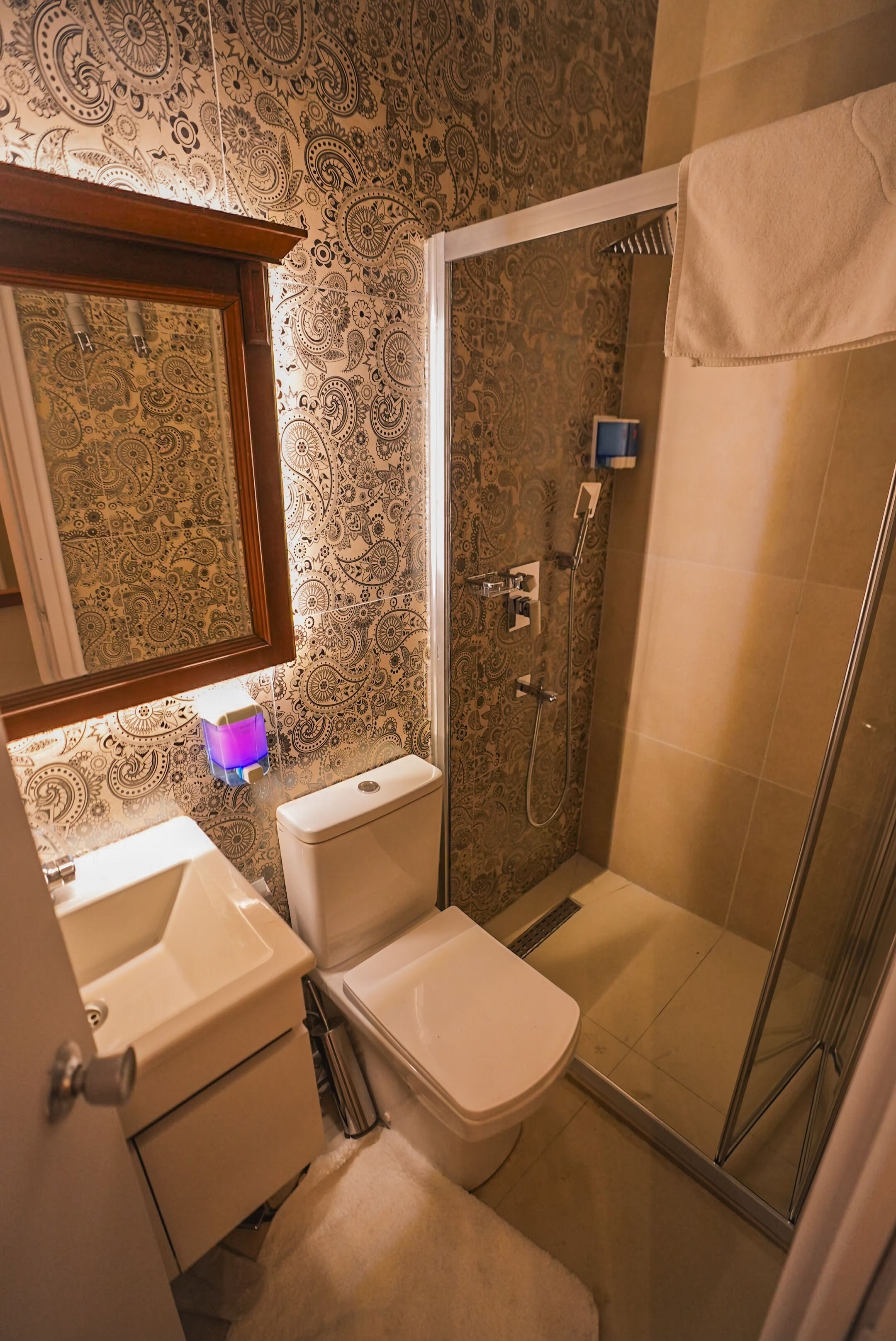 Ein Badezimmer mit Dusche, Toilette, Waschbecken und Spiegel.