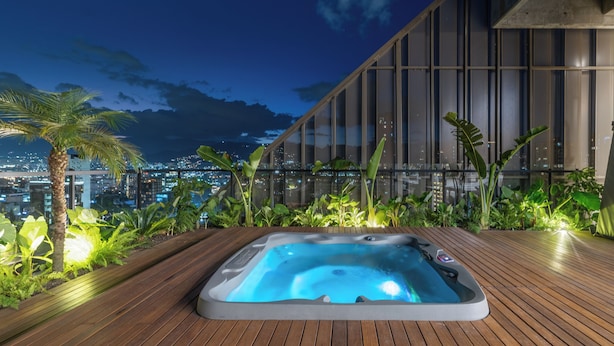 Un jacuzzi en una terraza de madera con vistas a la ciudad, de noche.