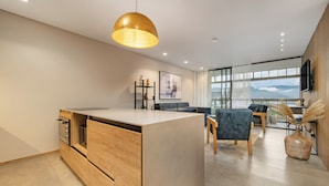 Una cocina moderna con una isla central, armarios de madera y una lámpara colgante.