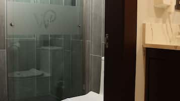 A modern bathroom with a glass-enclosed shower, a toilet, and a towel rack.