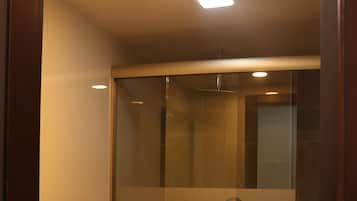 Un baño moderno con cabina de ducha de vidrio, inodoro blanco y suelo de baldosas de mármol.