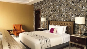 A hotel room with a large bed, two bedside tables, a nightstand, a chair, and a marble coffee table.