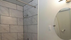 A modern bathroom with a walk-in shower, a toilet, and a sink with a mirror. - The Lagrange Inn & Extended Stay (Pleasant Valley)
