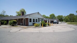 A building with a parking lot, a covered area, and a few cars parked. - The Lagrange Inn & Extended Stay (Pleasant Valley)