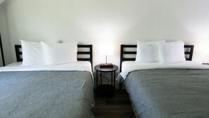 A hotel room with two single beds, a small round table, and a lamp. - The Lagrange Inn & Extended Stay (Pleasant Valley)