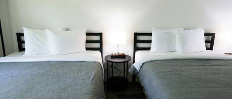A hotel room with two single beds, a small round table, and a lamp.